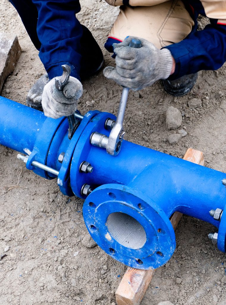 Workers installing water supply pipeline system, close up.